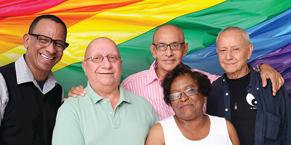 Email Updates - Five older adults standing in front of Pride flag. Photo Credit Ari Seth Cohen